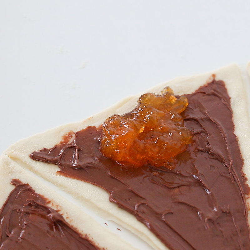 A dollop of apricot jam has been placed onto the puff pastry.