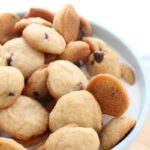 A close up of a blue bowl that is filled with mini cookies and milk.