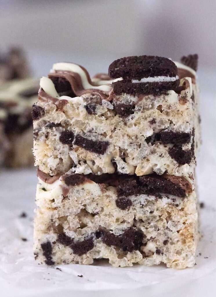 Two squares of oreo rice krispie treats stacked on a white table.