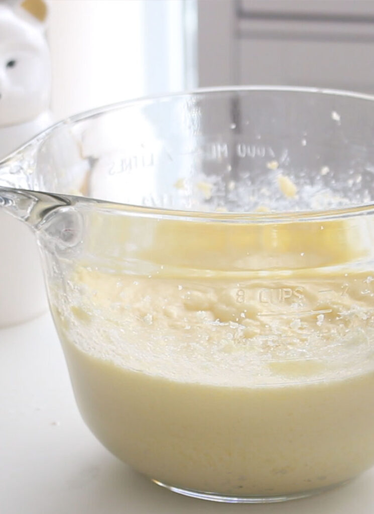 A large glass bowl containing vanilla cake batter.