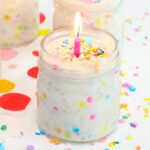overnight oats with confetti sprinkles in a small mason jar, topped with a pink lit candle and sprinkles