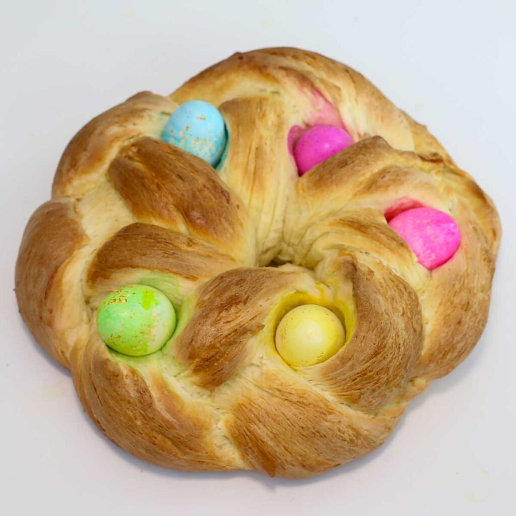 A baked and golden loaf of braided bread decorated with hard boiled eggs.