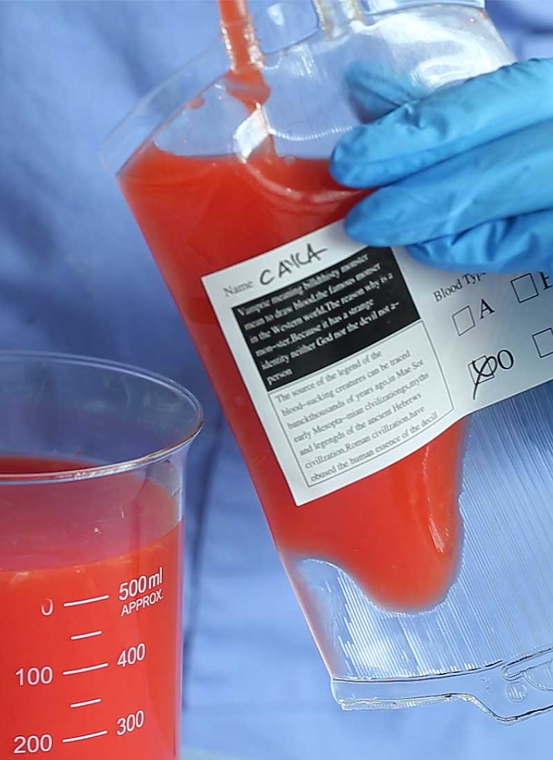 A clear blood bag is being filled with red juice.