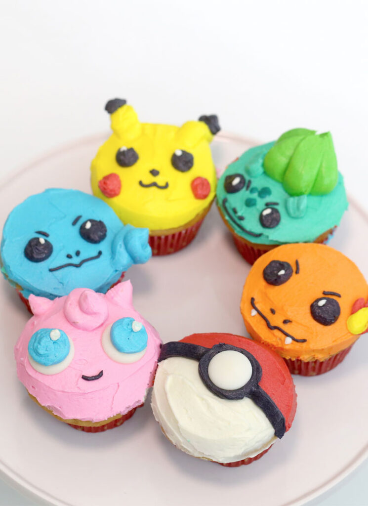 Pokemon cupcakes are arranged in a ring on a white cake stand.