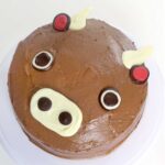 a chocolate cake on a white table, decorated like a cow