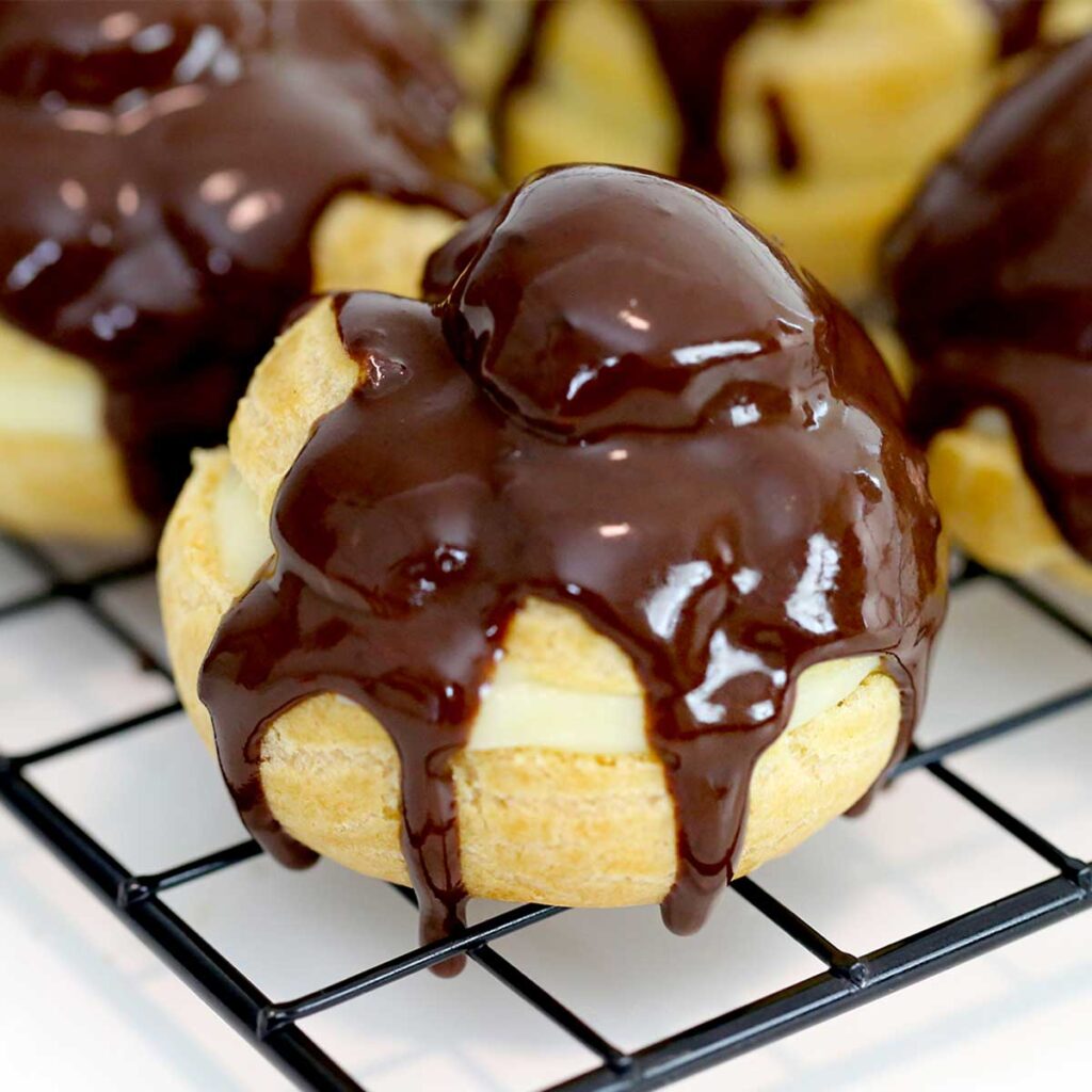 a cream puff filled with pastry cream and drizzled with chocolate