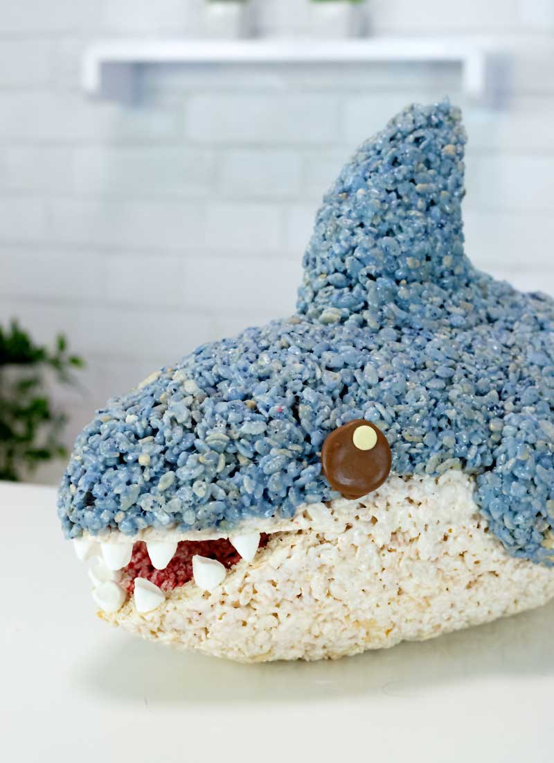 A smiling rice krispie treat shark on a white table