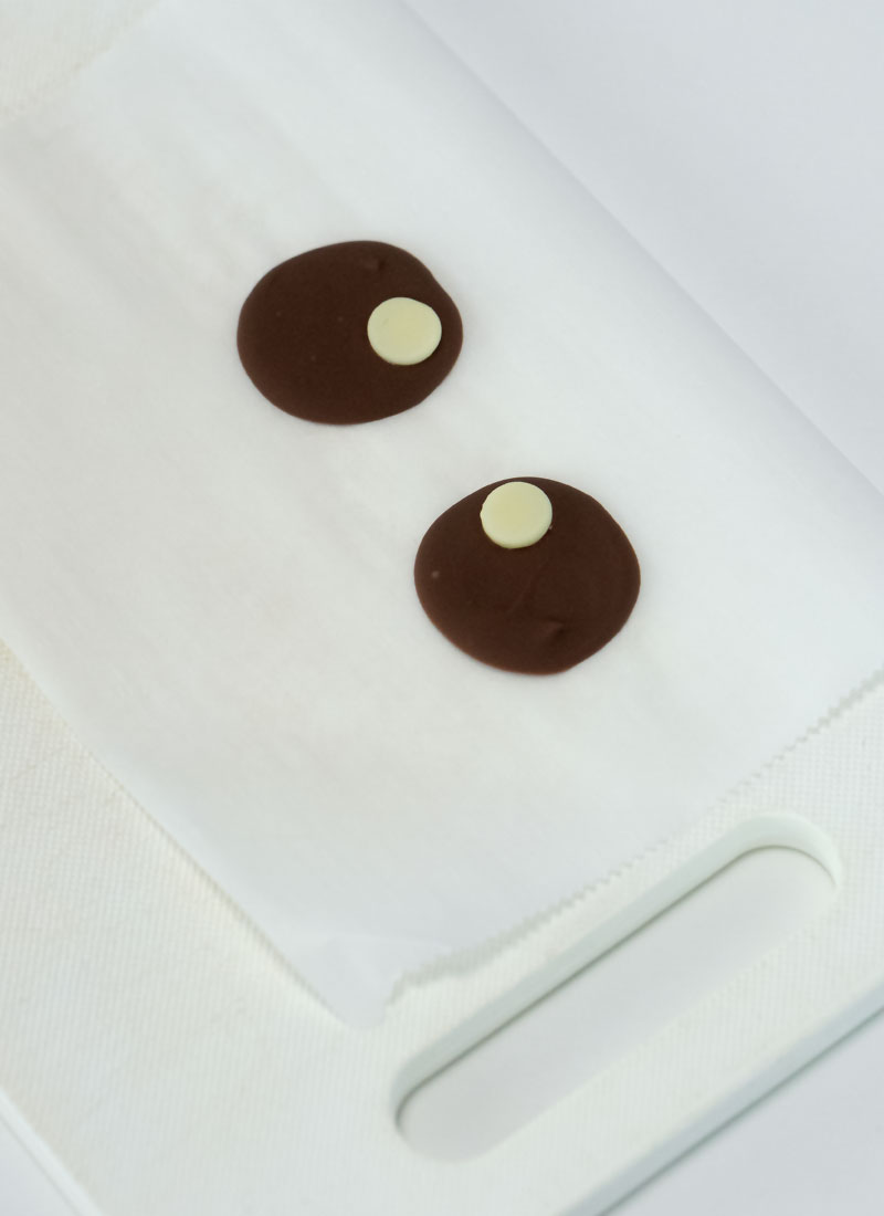Dark chocolate eyes with white chocolate pupils on a white cutting board