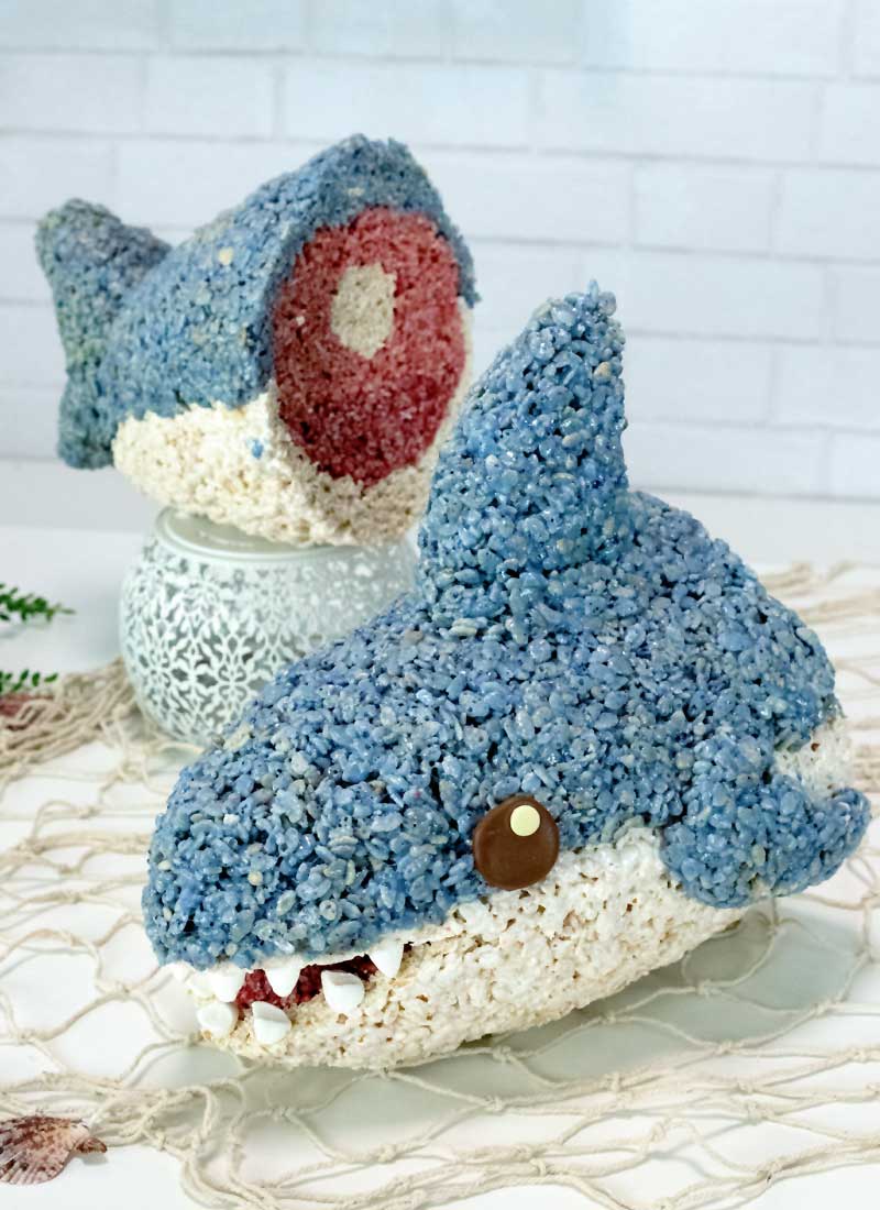 A cereal treat shark is cut in half. Placed on fish net and a white table