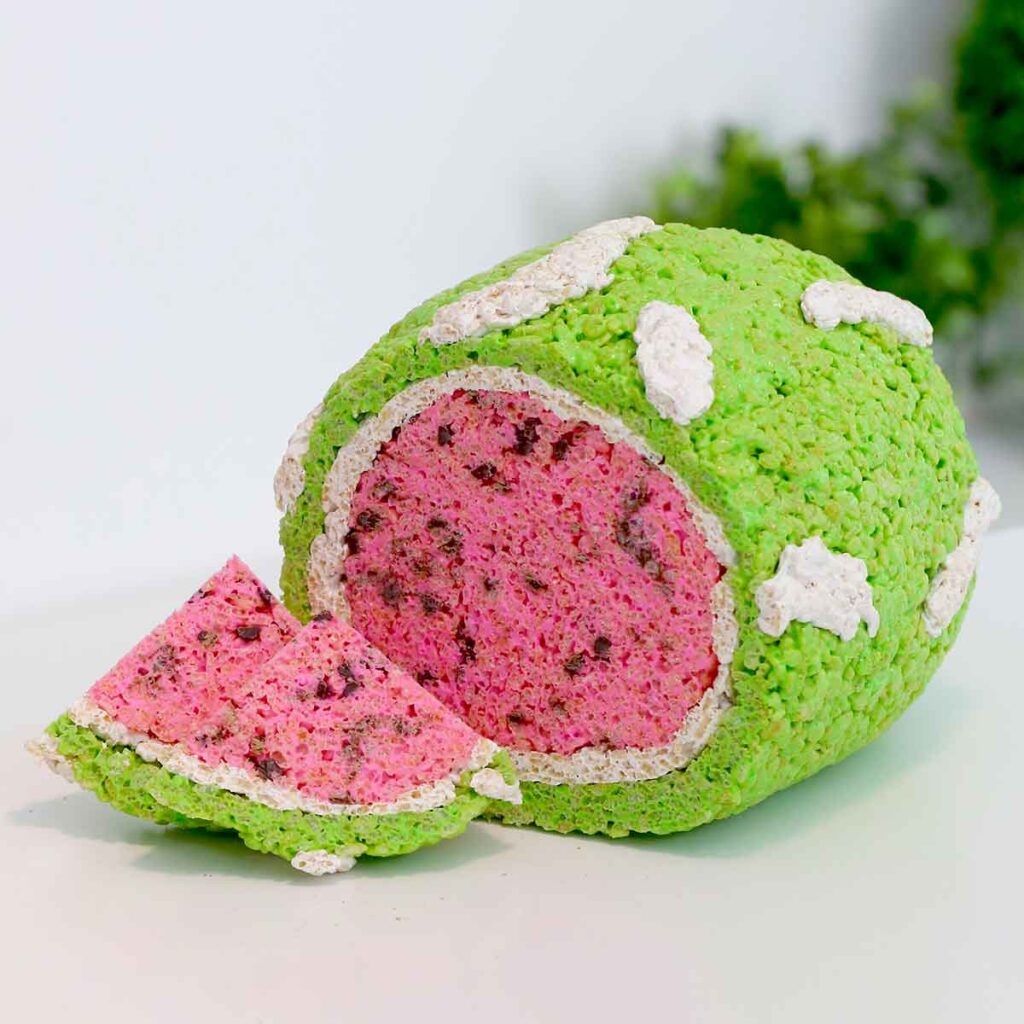 A watermelon made of cereal treats has been sliced and placed on a white table