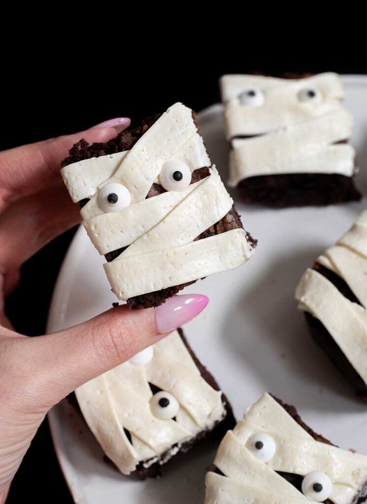 A hand is holding a mummy brownie up to the camera.