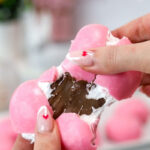 A pink chocolate heart is being pulled apart, revealing the marshmallow and nutella filling.