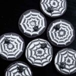 A top down view of the spider web cookies on a flat black table.