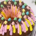 A close up of the Easter bundt cake. Mini eggs are sitting on the chocolate shavings, looking like a bird nest.
