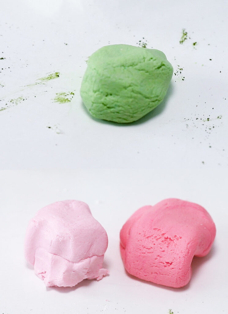 Three balls of green, pink and red mochi dough.