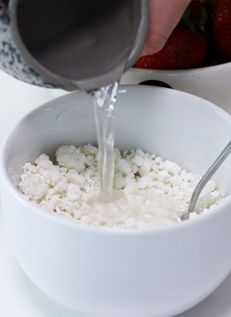 Water is being poured into a bowl containing rice flour.