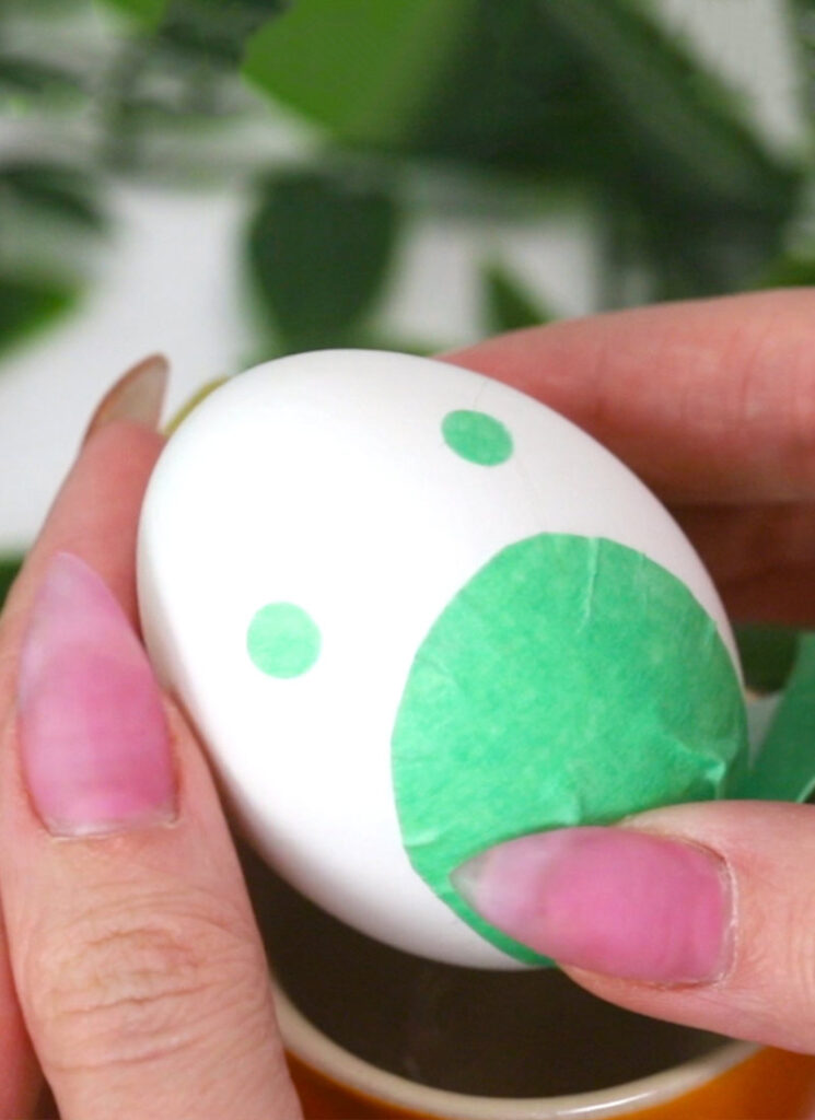 Two small green circles of tape have been stuck onto the Totoro egg shell.